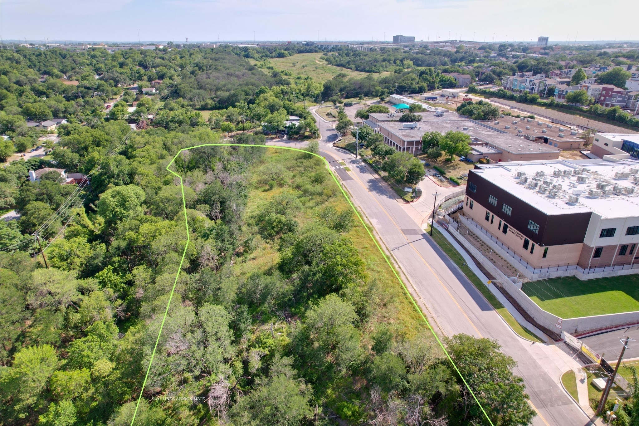 2813-2827 Metcalfe Road Austin, TX 78741 - Photo 6 of 13 A verdant, undeveloped land parcel offers ample space for new construction, bordered by a quiet road and established community.