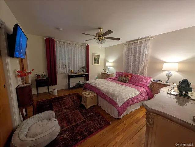 a spacious bedroom with a bed a couch and a flat tv screen on the dresser