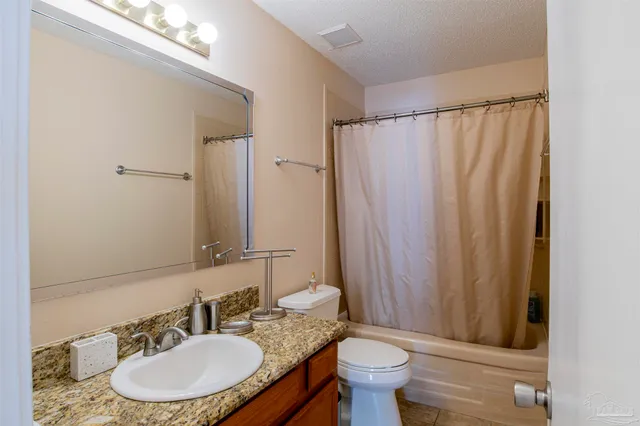a bathroom with a granite countertop sink toilet and a mirror