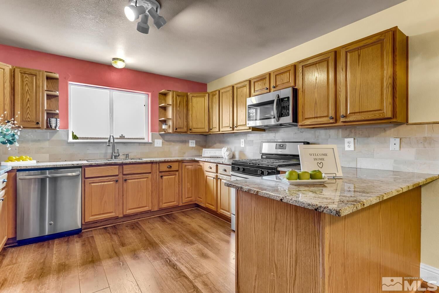 1031 University Ridge Drive Reno, NV 89512 - Photo 7 of 38 a kitchen with stainless steel appliances granite countertop wooden cabinets a stove top oven a sink and dishwasher