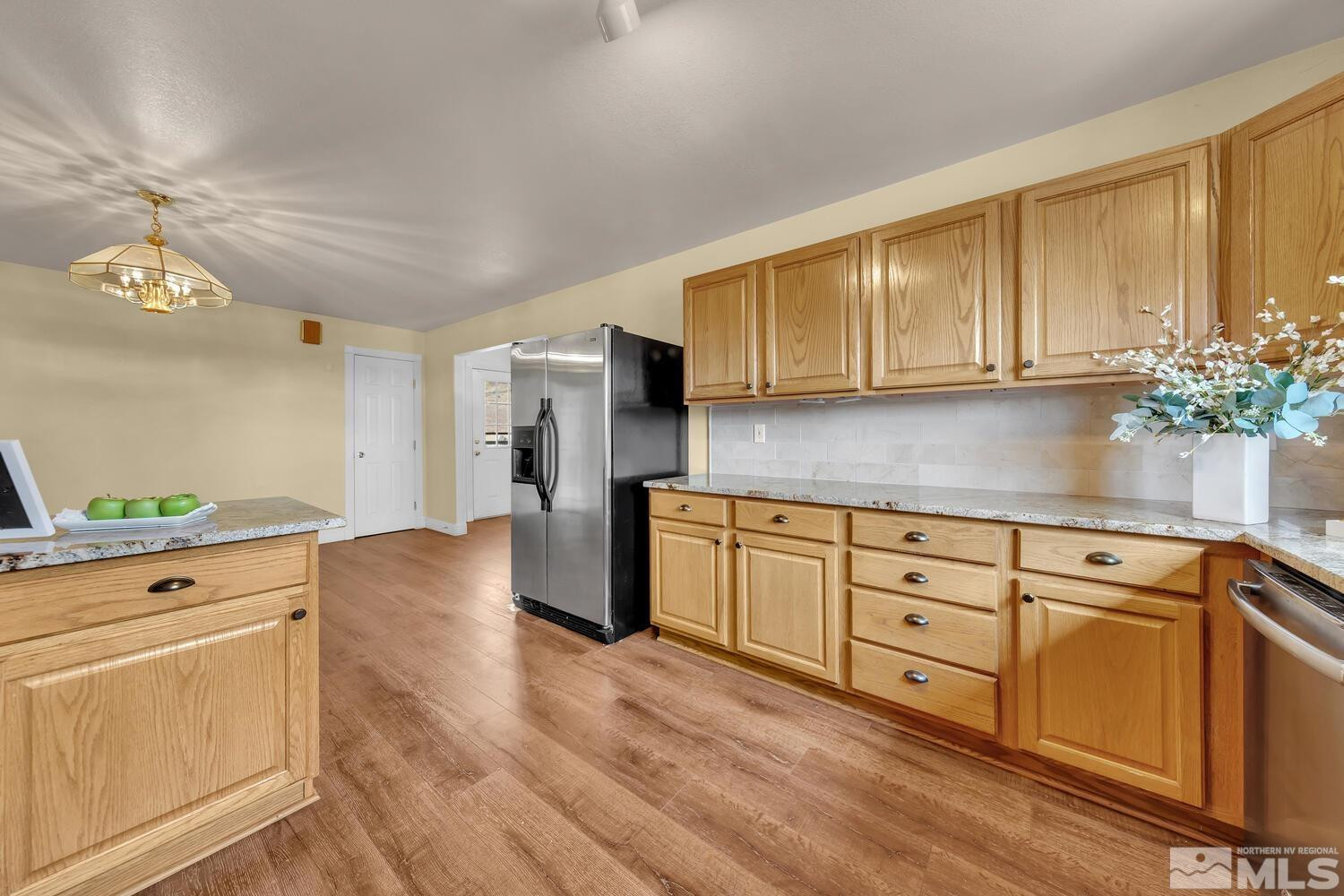 1031 University Ridge Drive Reno, NV 89512 - Photo 8 of 38 a kitchen with stainless steel appliances kitchen island granite countertop a refrigerator a sink dishwasher and white cabinets with wooden floor