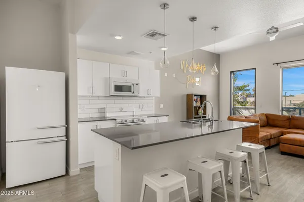 a kitchen with stainless steel appliances granite countertop a sink a stove a refrigerator a center island and furniture