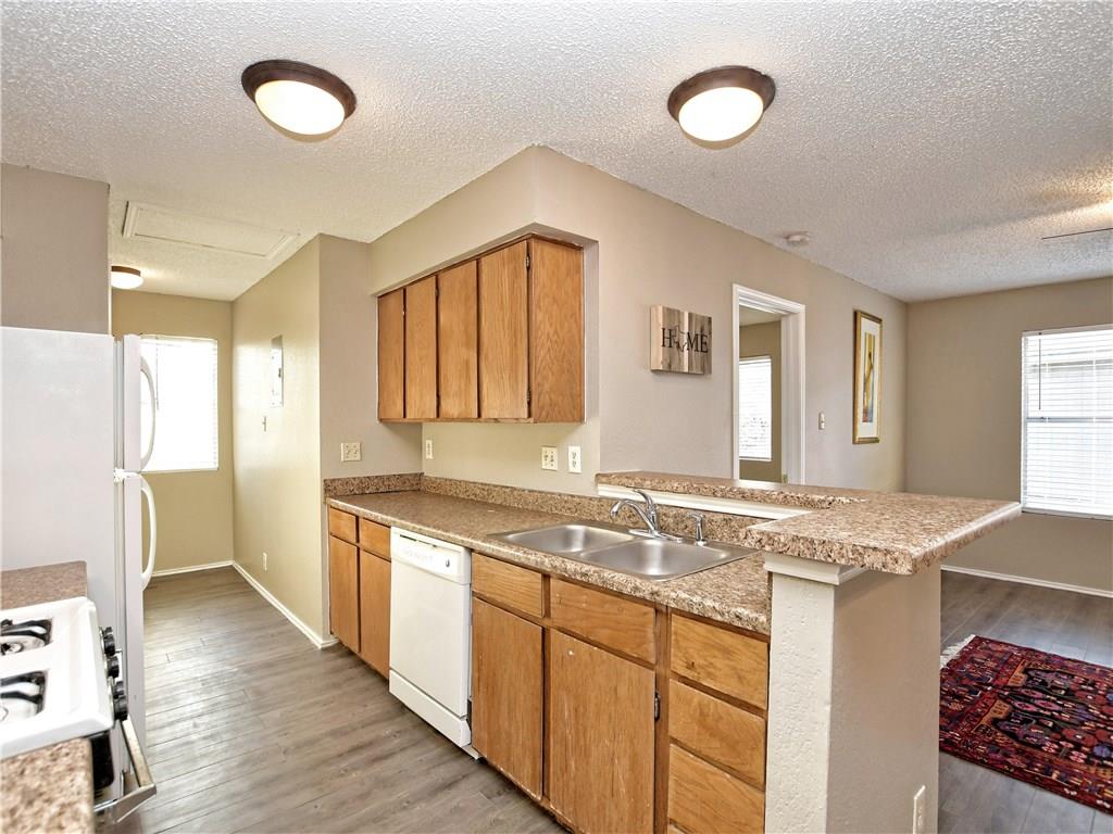 5401 Spring Meadow Road, Unit B Austin, TX 78744 - Photo 9 of 21 Functional kitchen with ample cabinet space, a convenient breakfast bar, and wood flooring.
