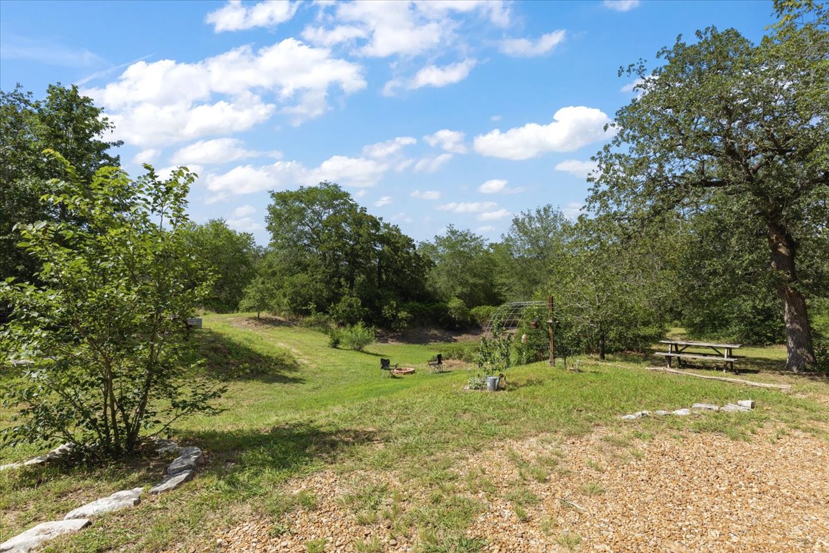 1705 Makinson Road West Point, TX 78963 - Photo 28 of 40 A verdant, open yard with a gravel path leads to a picnic area and lush trees.