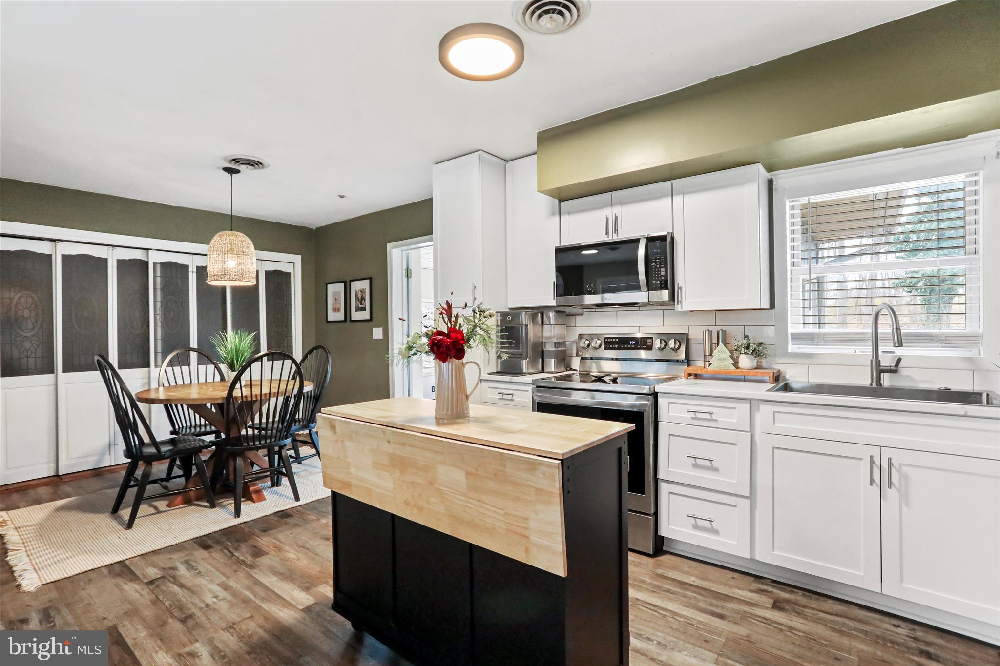 7879 Talhelm Road Chambersburg, PA 17202 - Photo 17 of 43 a kitchen with stainless steel appliances granite countertop a stove top oven a sink dishwasher a dining table and chairs with wooden floor