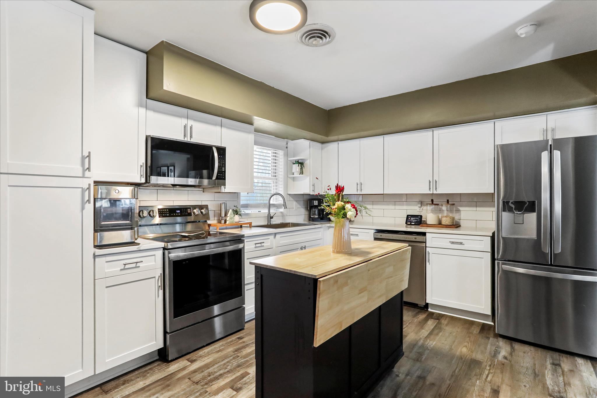 7879 Talhelm Road Chambersburg, PA 17202 - Photo 21 of 43 a kitchen with a sink a stove a refrigerator and white cabinets