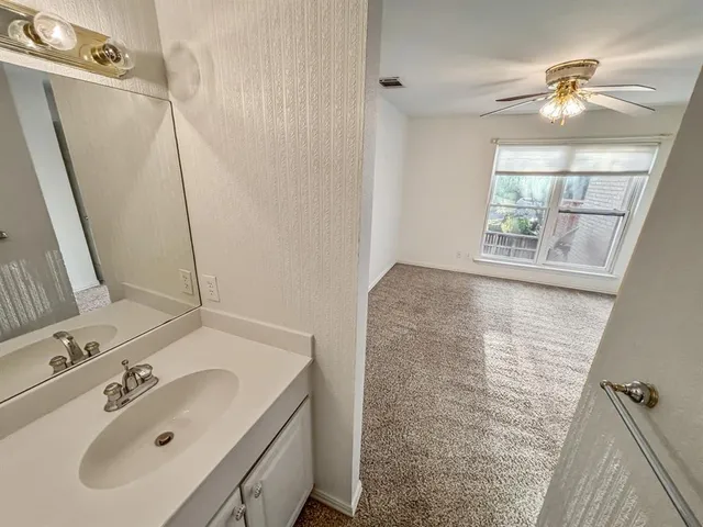 a view of an empty room and chandelier fan