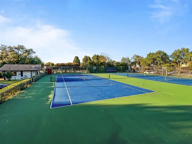 a view of a brick house with a small yard plants and large tree