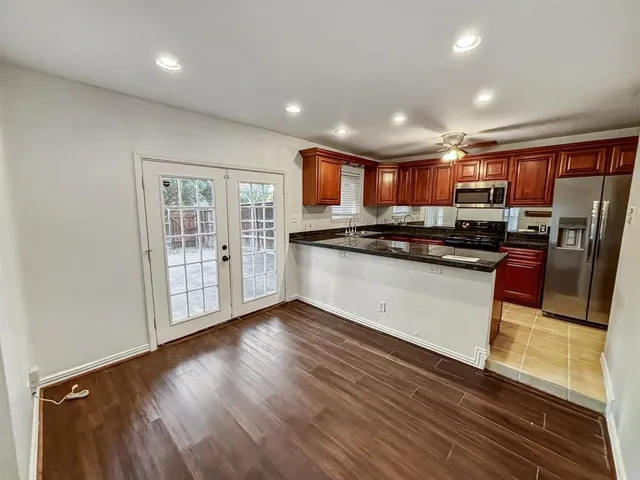 a kitchen with stainless steel appliances granite countertop a refrigerator a sink dishwasher a stove and a microwave oven with wooden floor