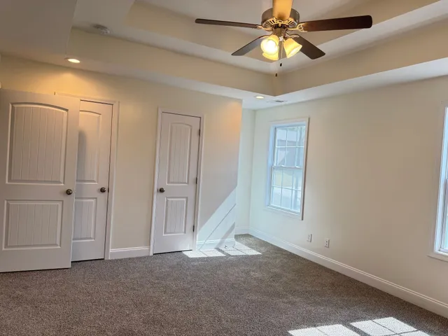 a view of an empty room with window and chandelier fan