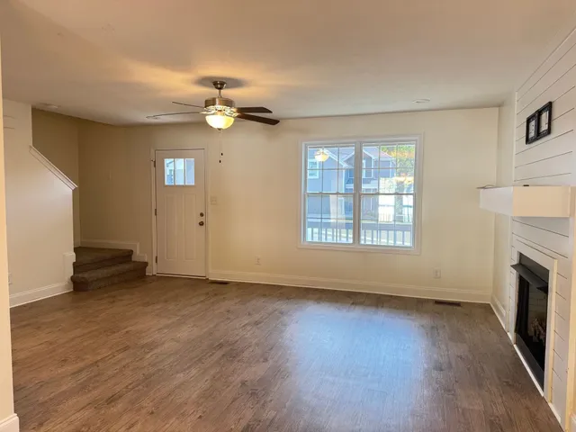 an empty room with wooden floor fireplace and windows