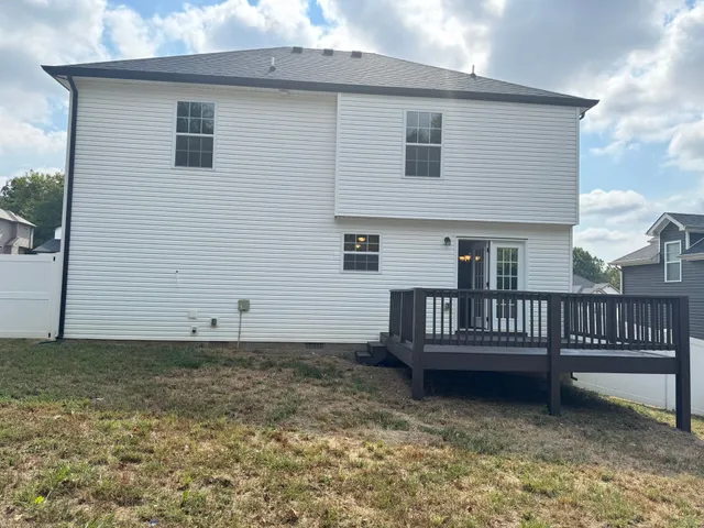 a view of a house with wooden fence and a yard