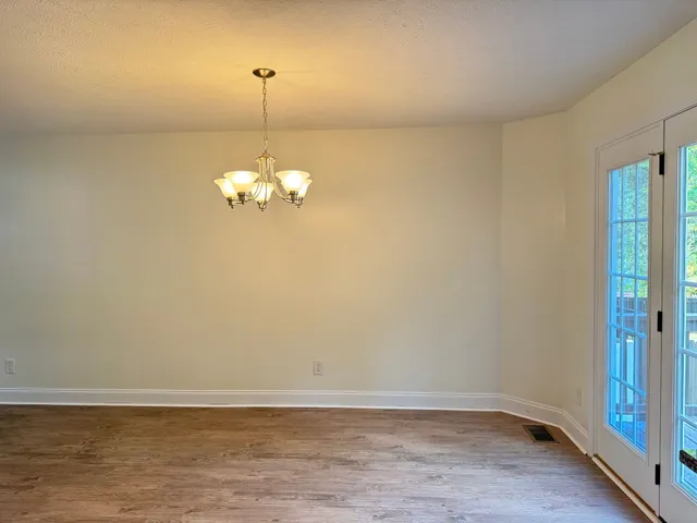 a room with a chandelier fan and wooden floor
