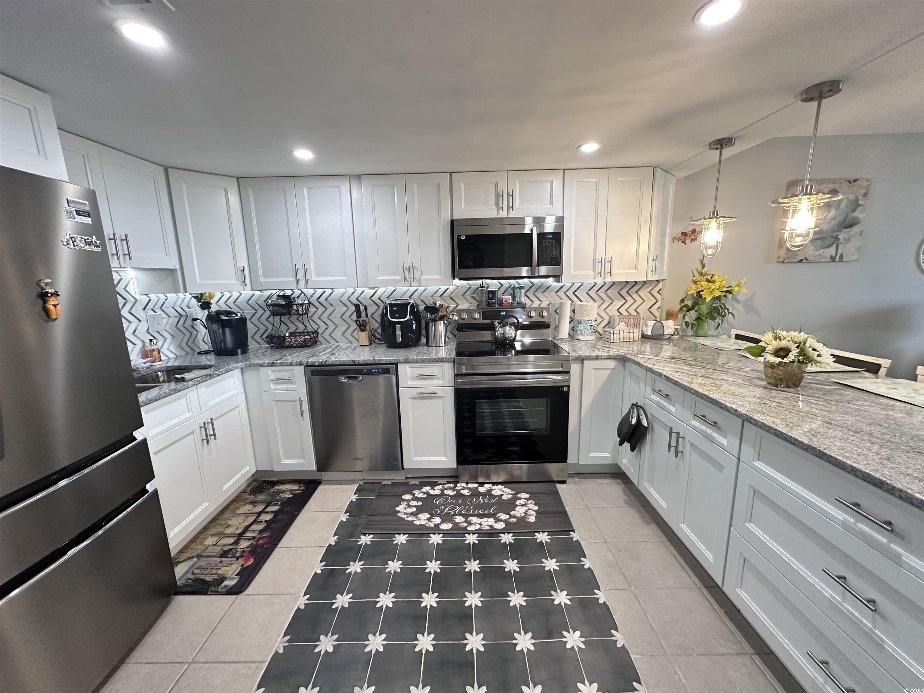 601 Mitchell Drive, Unit 1401 Myrtle Beach, SC 29577 - Photo 3 of 25 Kitchen featuring decorative backsplash, appliances with stainless steel finishes, white cabinetry, light stone counters, and recessed lighting