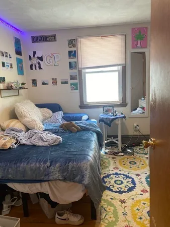 a bed sitting in a bedroom next to a window with computer on a table