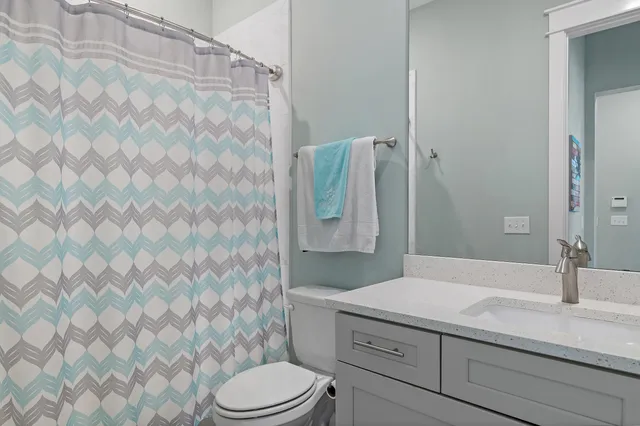 a bathroom with a granite countertop sink and a toilet