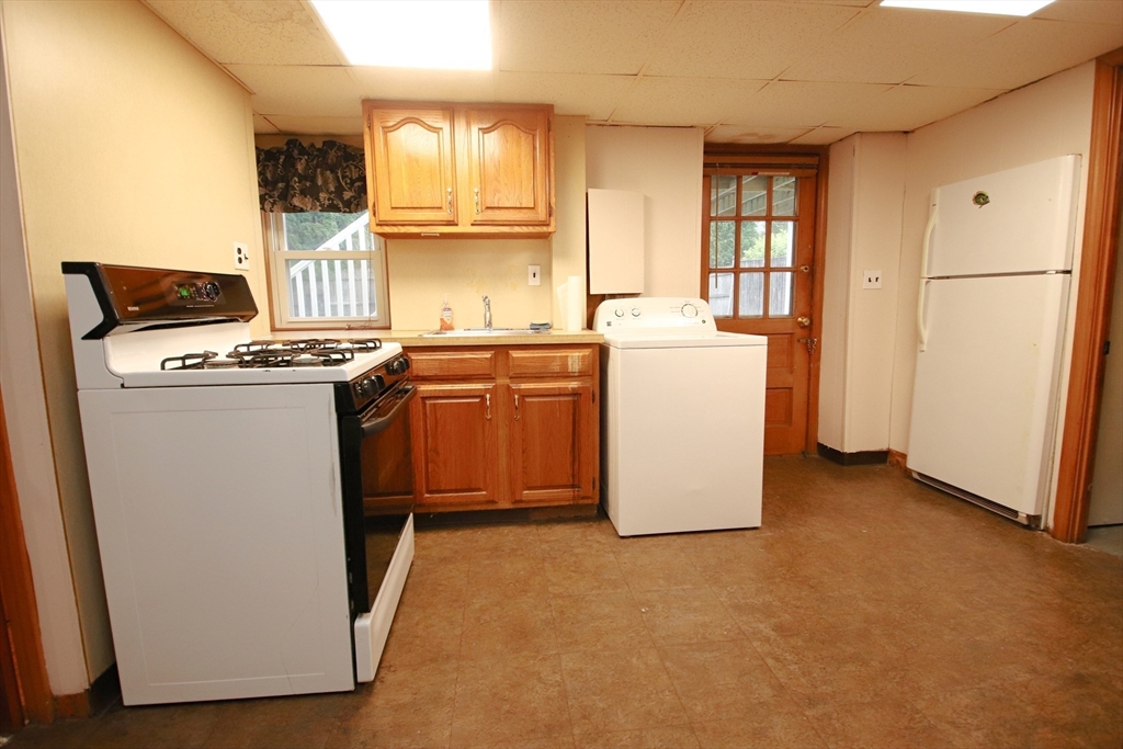 61 Central Street Saugus, MA 01906 - Photo 31 of 42 a kitchen with a stove a refrigerator and white cabinets
