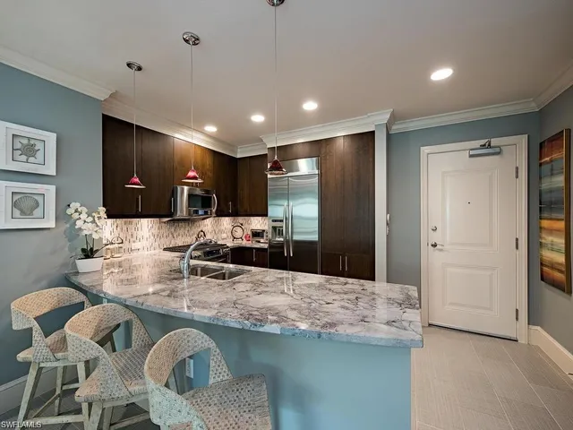 a kitchen with kitchen island granite countertop a sink and refrigerator