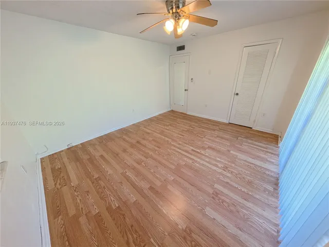 an empty room with wooden floor and fan