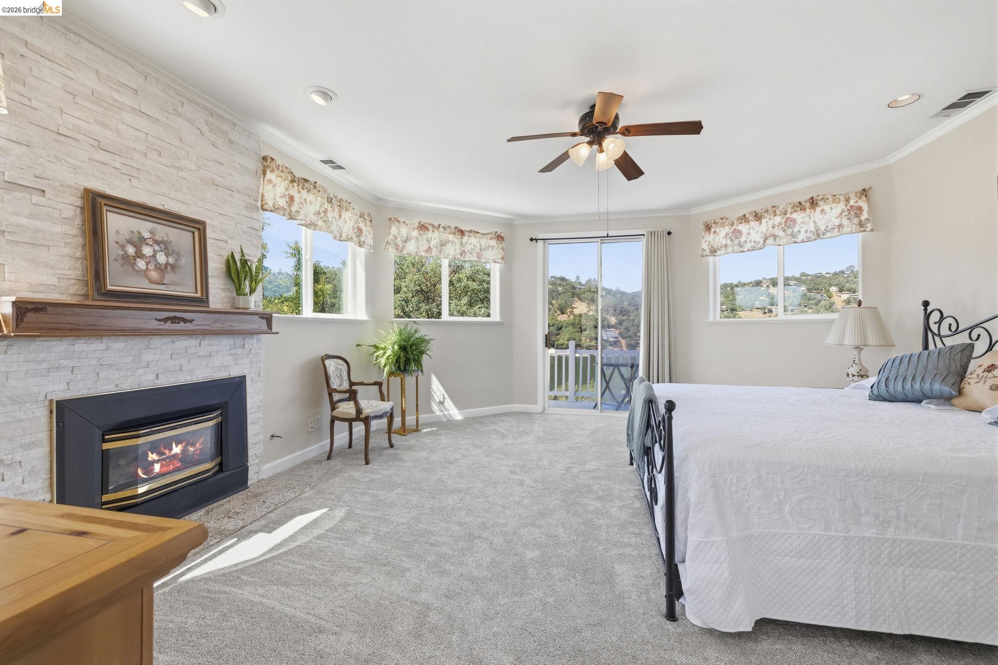 6242 Bluff View Road Copperopolis, CA 95228 - Photo 31 of 59 Spacious room featuring a stone-faced fireplace with wood mantel, NEW light gray carpeting, and multiple windows including a sliding glass door out to the new deck where you will find a sitting area to enjoy the lake views.