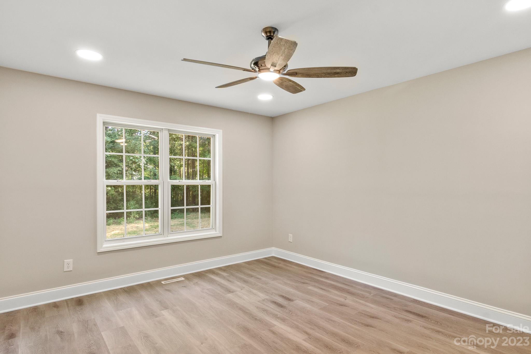 313 Faith Road Mooresville, NC 28115 - Photo 22 of 42 an empty room with wooden floor chandelier fan and windows