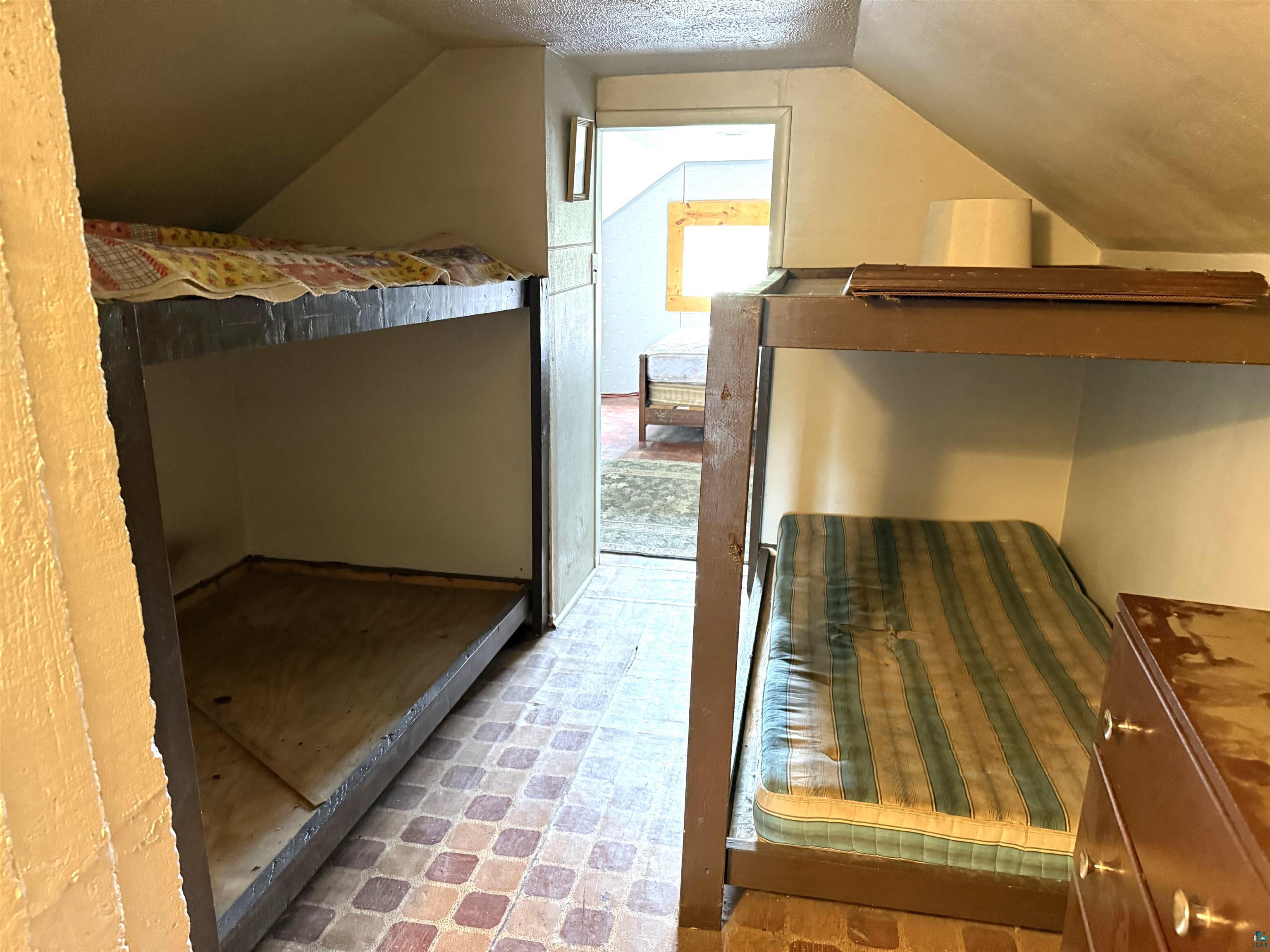 3541 Bent Trout Lake Road Barnum, MN 55707 - Photo 23 of 41 Compact sleeping area featuring built-in bunk beds, sloped ceilings, and patterned tile flooring