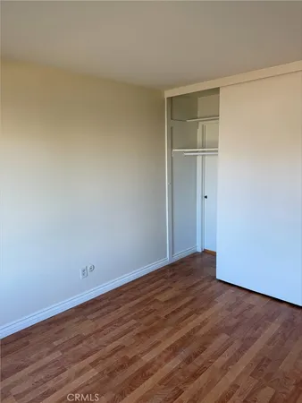 a view of an empty room with wooden floor and closet