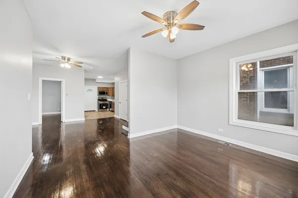 a view of an empty room with a window and wooden floor