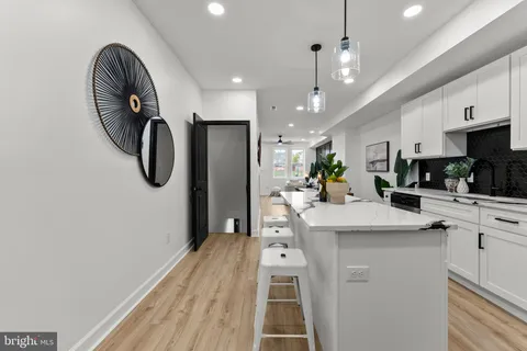 a kitchen with stainless steel appliances granite countertop a sink a stove a refrigerator and island with wooden floor