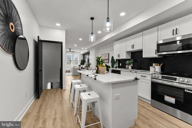 a kitchen with stainless steel appliances granite countertop a refrigerator a stove top oven a sink dishwasher and white cabinets with wooden floor