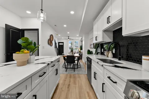 a kitchen with kitchen island granite countertop a sink a counter space appliances and cabinets