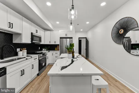 a kitchen with a sink stainless steel appliances and white cabinets