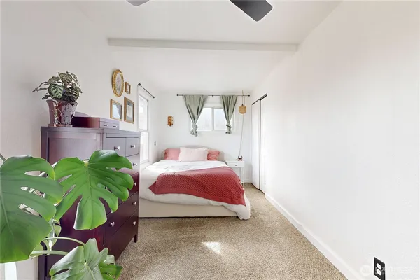 a bedroom with a bed potted plant on the dresser and mirror