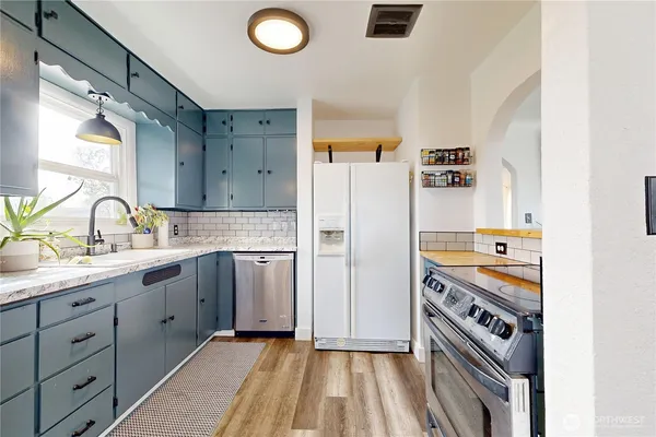 a kitchen with stainless steel appliances granite countertop a refrigerator a sink and white cabinets