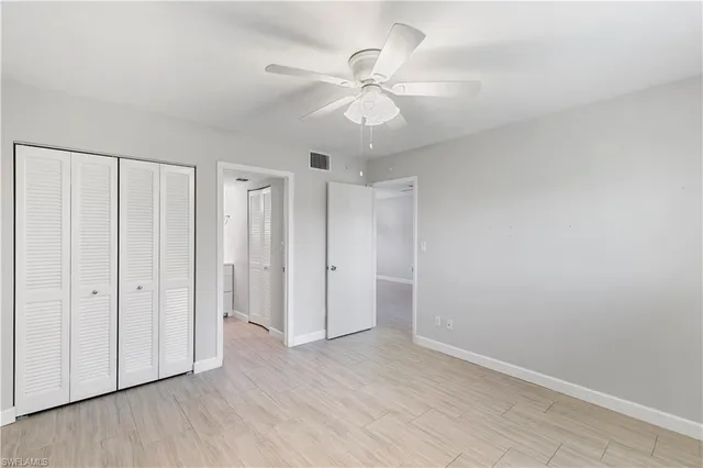 an empty room with wooden floor fan and windows