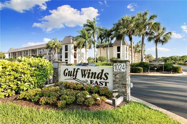 a view of sign board with buildings in background