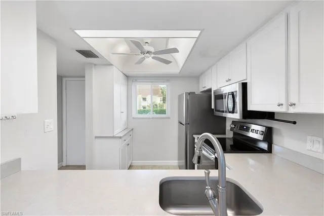 a kitchen with stainless steel appliances a sink a stove and a refrigerator with wooden floor