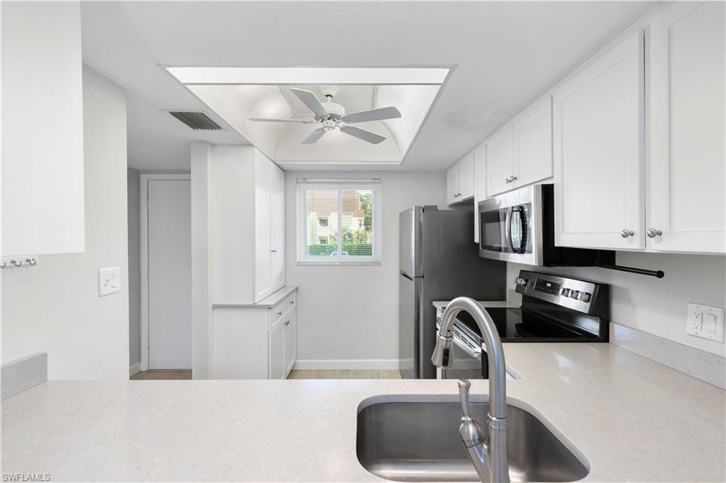 1008 Manatee Road, Unit G103 Naples, FL 34114 - Photo 4 of 24 a kitchen with stainless steel appliances a sink a stove and a refrigerator with wooden floor