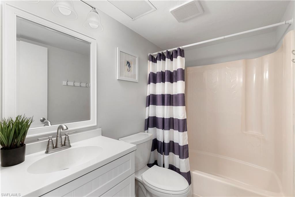 1008 Manatee Road, Unit G103 Naples, FL 34114 - Photo 10 of 24 a bathroom with a sink a toilet a shower curtain and a mirror