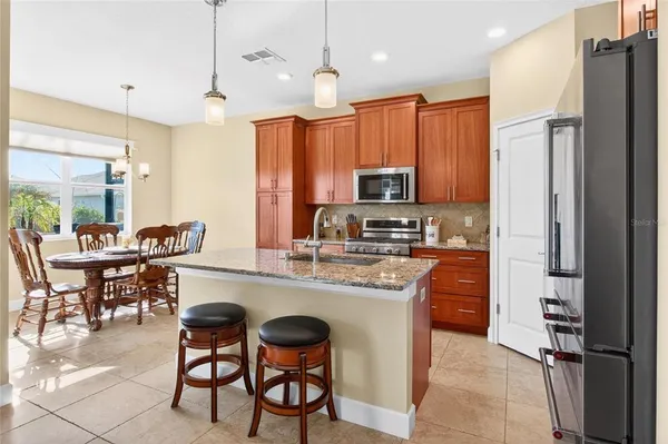 a kitchen with stainless steel appliances granite countertop a stove a refrigerator a kitchen island with a dining table and chairs