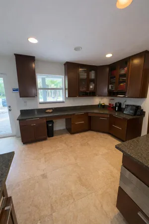 a large kitchen with kitchen island granite countertop a sink and a stove top oven with wooden floor