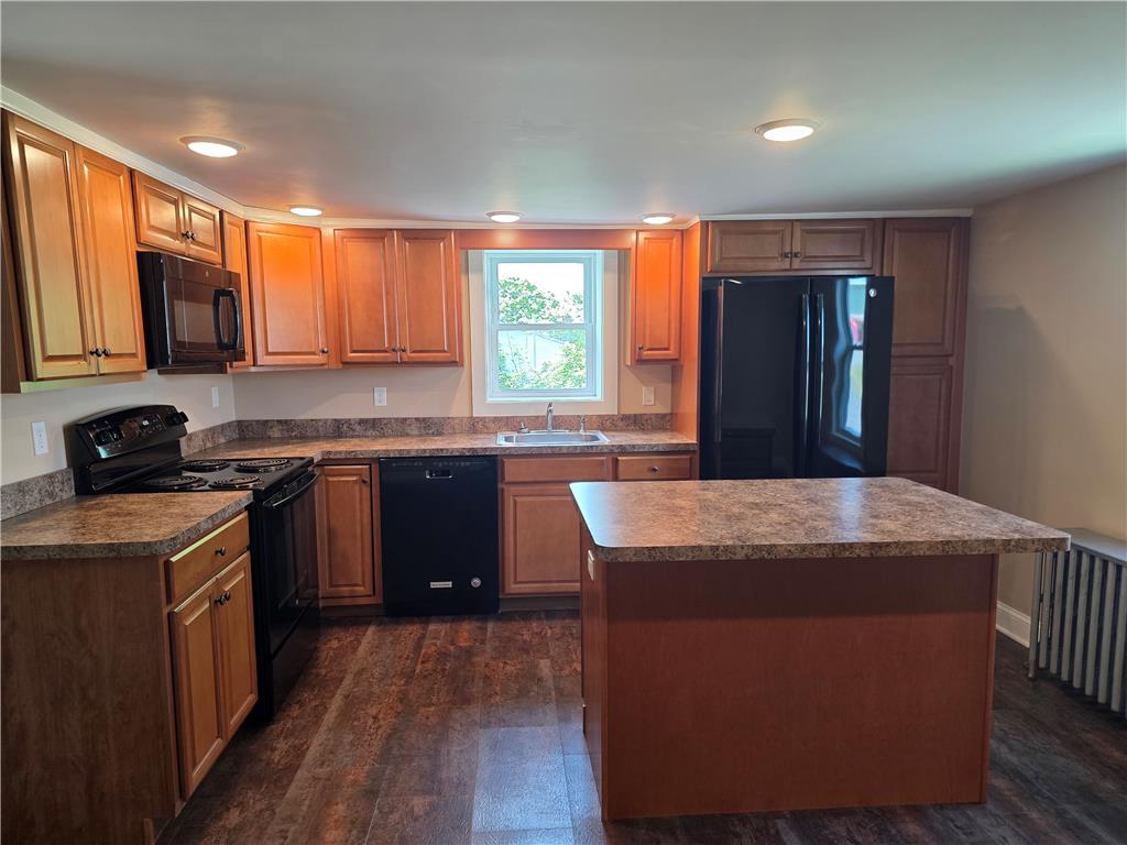 5166 Springmill Road Whitehall, PA 18052 - Photo 9 of 29 A functional kitchen features rich wood cabinetry, a central island, and modern black appliances.
