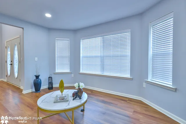 a kitchen with stainless steel appliances granite countertop a refrigerator a microwave oven a sink dishwasher and a dining table with wooden floor