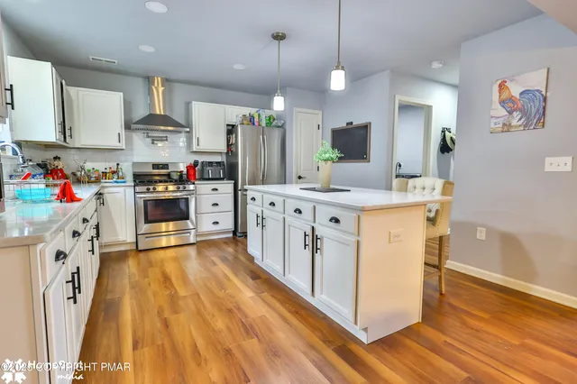 a kitchen with stainless steel appliances a table chairs refrigerator and microwave