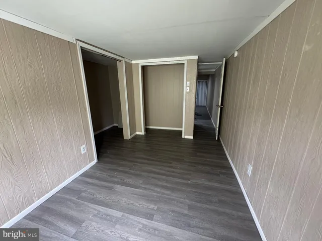 a view of an empty room with wooden floor and closet