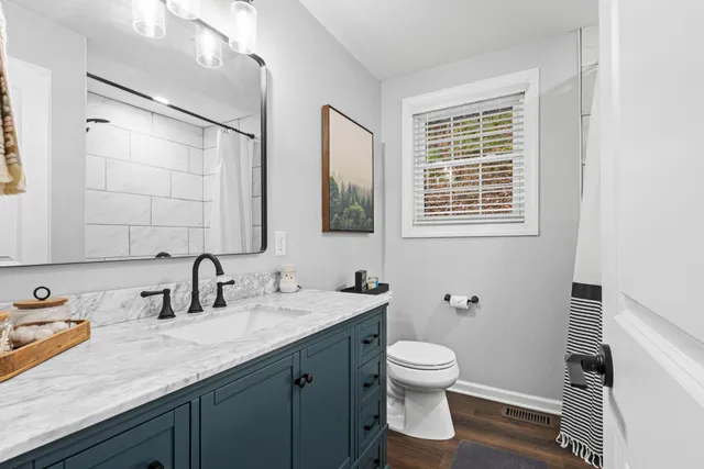 a bathroom with a toilet sink a mirror and shower