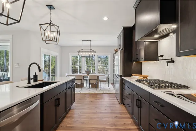 a kitchen with stainless steel appliances granite countertop a sink a stove top oven a counter space and cabinets
