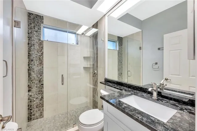 a bathroom with a double vanity sink toilet mirror and shower