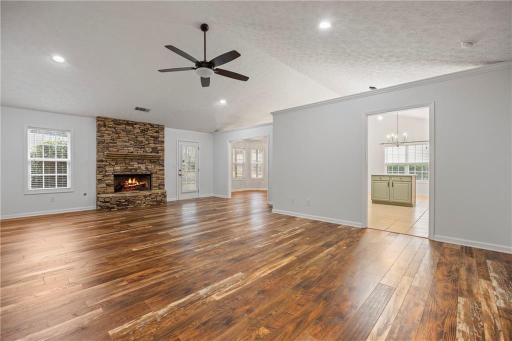 3768 North Sharon Church Road Loganville, GA 30052 - Photo 7 of 58 a view of an empty room with wooden floor ceiling fan and windows