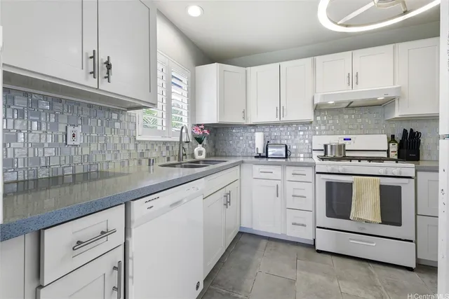 a kitchen with granite countertop white cabinets white stainless steel appliances with a sink and dishwasher